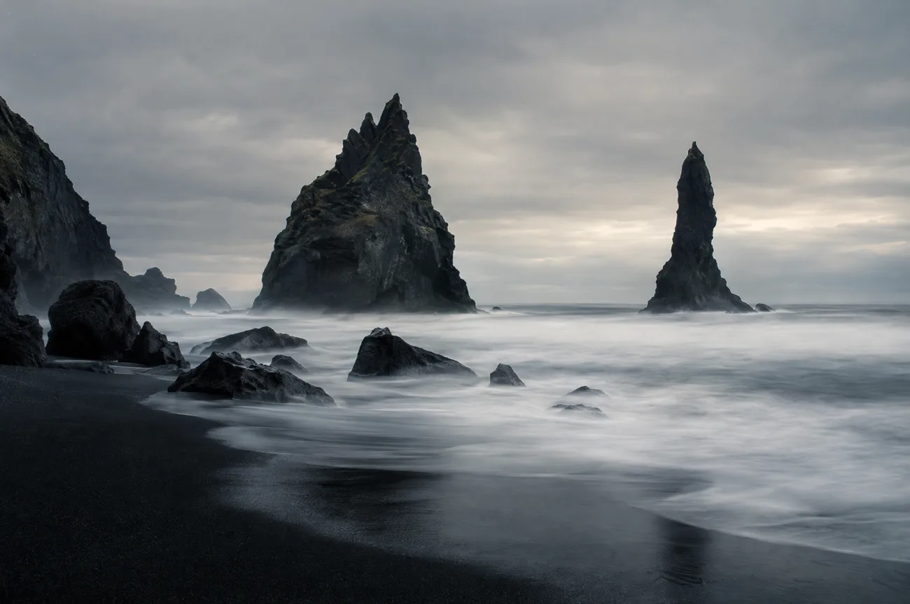 Sea stacks off a black volcanic beach in long exposure
